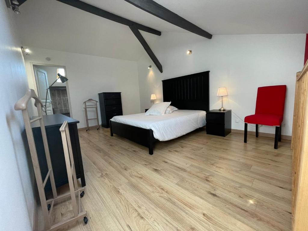sypialnia z łóżkiem i czerwonym krzesłem w obiekcie Les Logis des Vignobles Sainte Emilion en Duplex n 1 avec terrasse w mieście Saint-Émilion