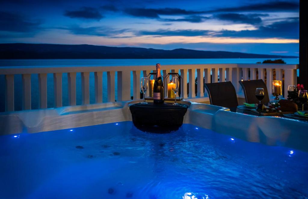 a hot tub on a balcony with bottles of wine at Adria Croatica in Lokva Rogoznica