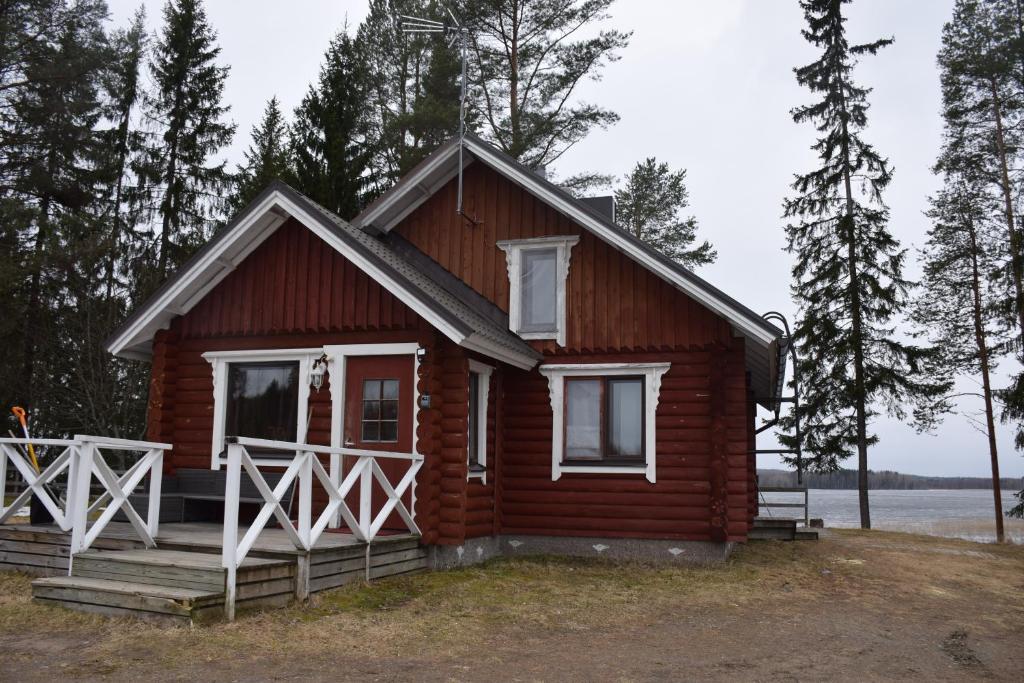 ein kleines Holzhaus mit einer Veranda und einem Zaun in der Unterkunft Kaijansaaren Lomamökit in Tölvä