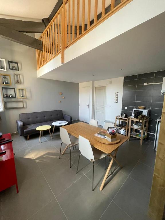 un salon avec une table et des chaises en bois dans l'établissement Les logis des Vignobles Sainte Emilion en Duplex n 3 avec terrasse, à Saint-Émilion