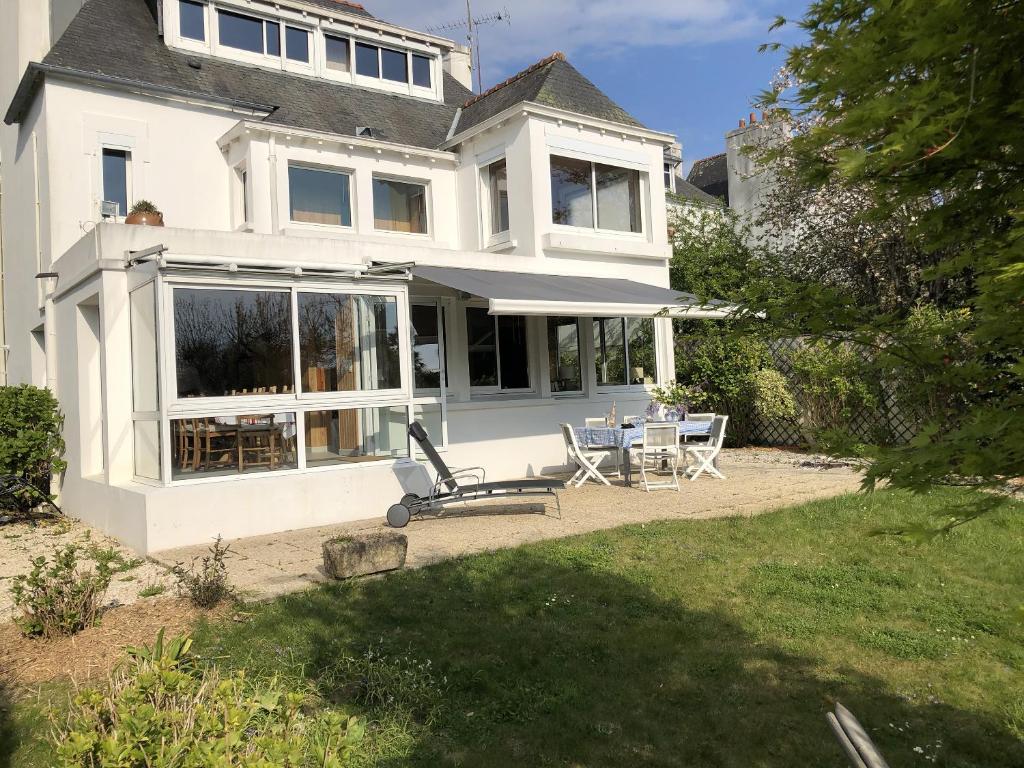 a white house with a table and chairs in the yard at Le Huic maison de marin lambrissée in Bénodet