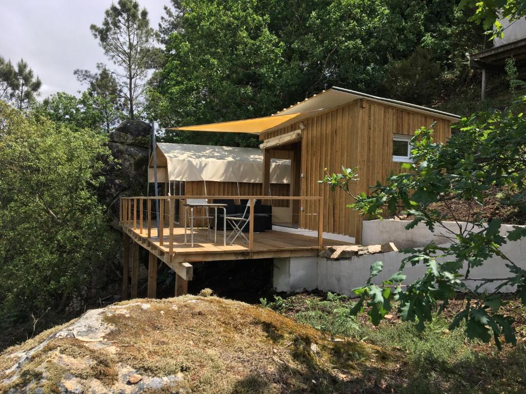 a wooden house with a deck in a yard at Glamping Cabana nas arvores in Ponte da Barca