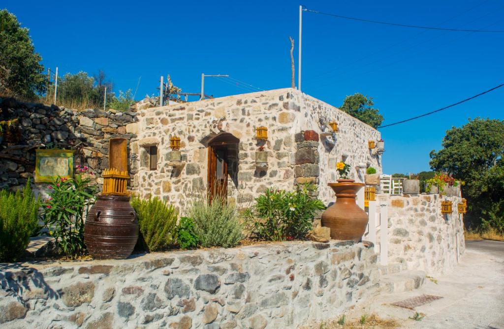 an old stone building with vases on a wall at Palaiokastro Traditional House in Mandrakion