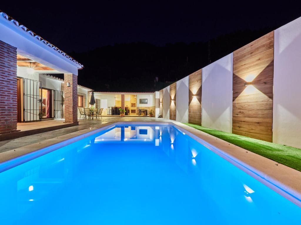 a swimming pool in the backyard of a house at night at Cubo's Finca El Nogal de los Montes de Malaga in Málaga