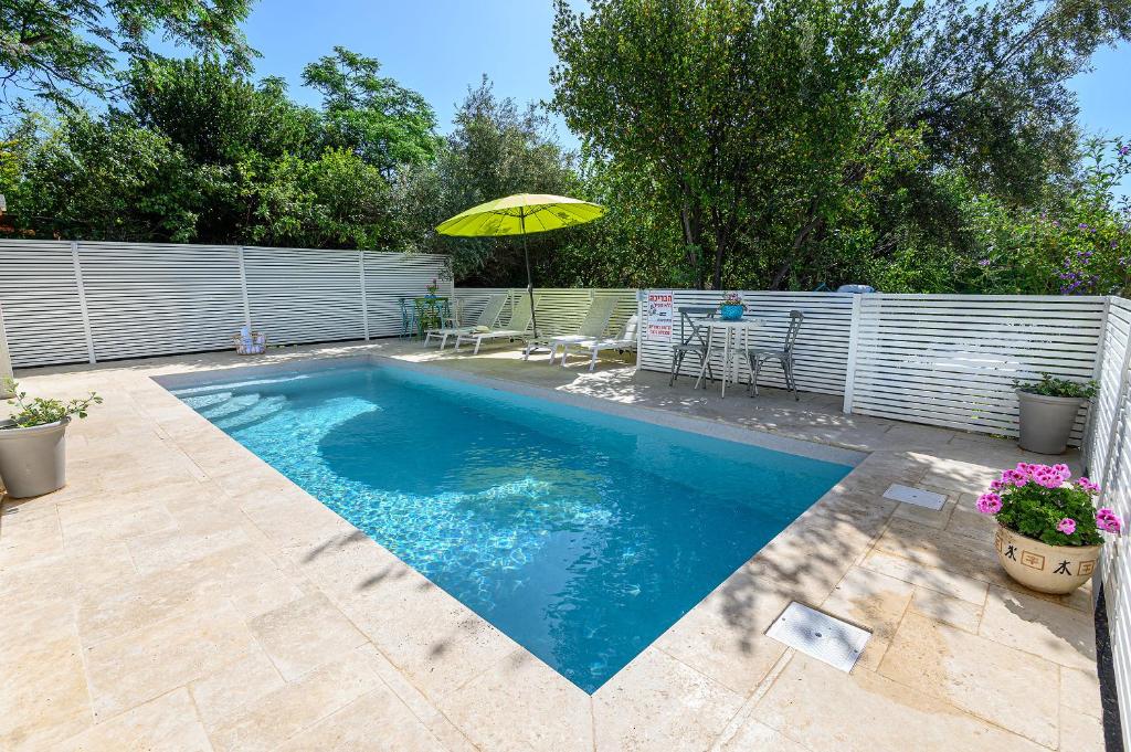 a swimming pool with an umbrella in a backyard at Marom Romance in Kahal