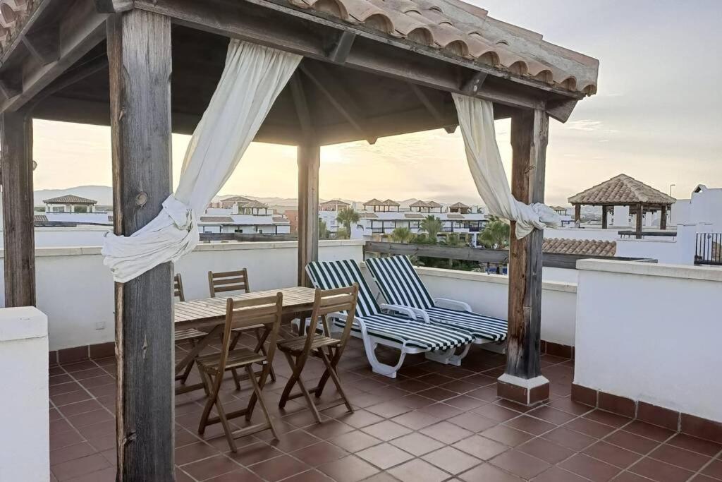 a wooden table and chairs on a roof at A TU VERA Apartamento en Vera Playa in Playas de Vera