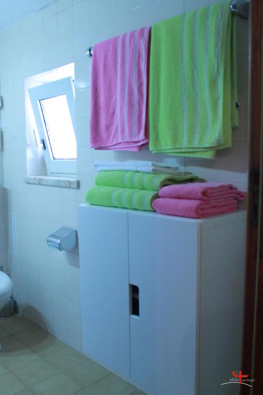 a bathroom with green and pink towels and a mirror at ABLA Guest House in Carcavelos