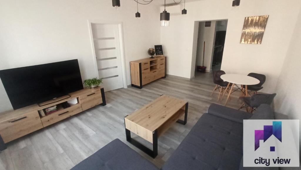ein Wohnzimmer mit einem Flachbild-TV und einem Tisch in der Unterkunft CITY VIEW Tołstoja - KLIMATYZACJA in Świdnica