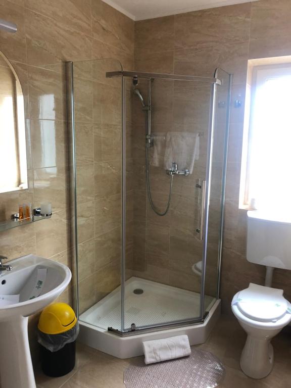 ein Badezimmer mit Dusche, Toilette und Waschbecken in der Unterkunft Elena-Maria Apartments in Buşteni