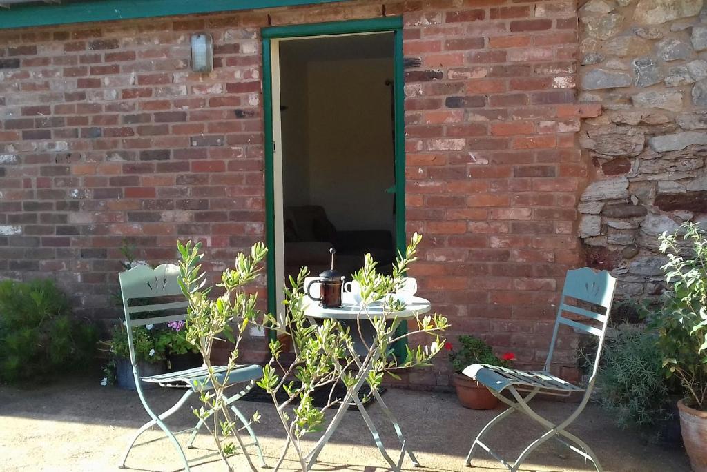 einen Tisch und zwei Stühle vor einem Backsteingebäude in der Unterkunft Courtbrook Farm in Exeter