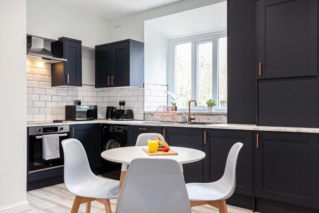 a kitchen with black cabinets and a white table and chairs at Hacken Lodge in Darcy Lever