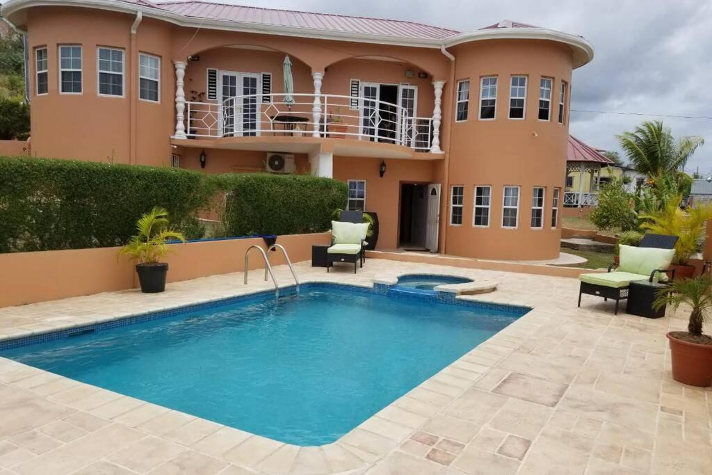 a villa with a swimming pool in front of a house at Shalom apartment in Scarborough