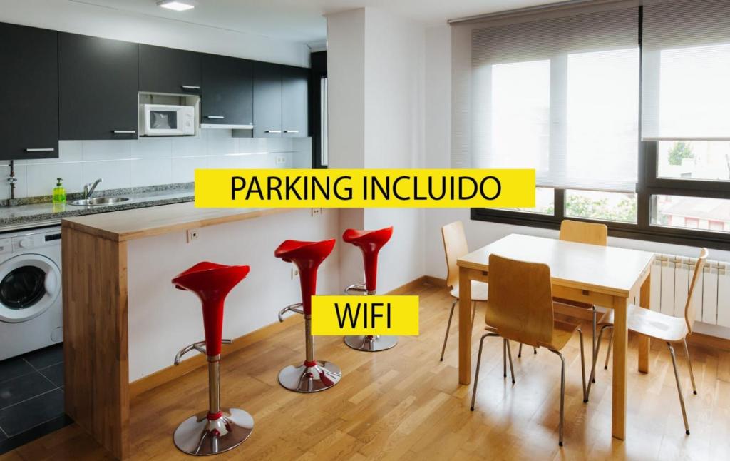une cuisine avec une table à manger et des tabourets rouges dans l'établissement Apartamento MyM, à Gijón