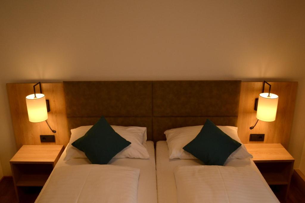 a bedroom with a bed with two pillows and two lights at Gasthof Kranerwirt in Lannach