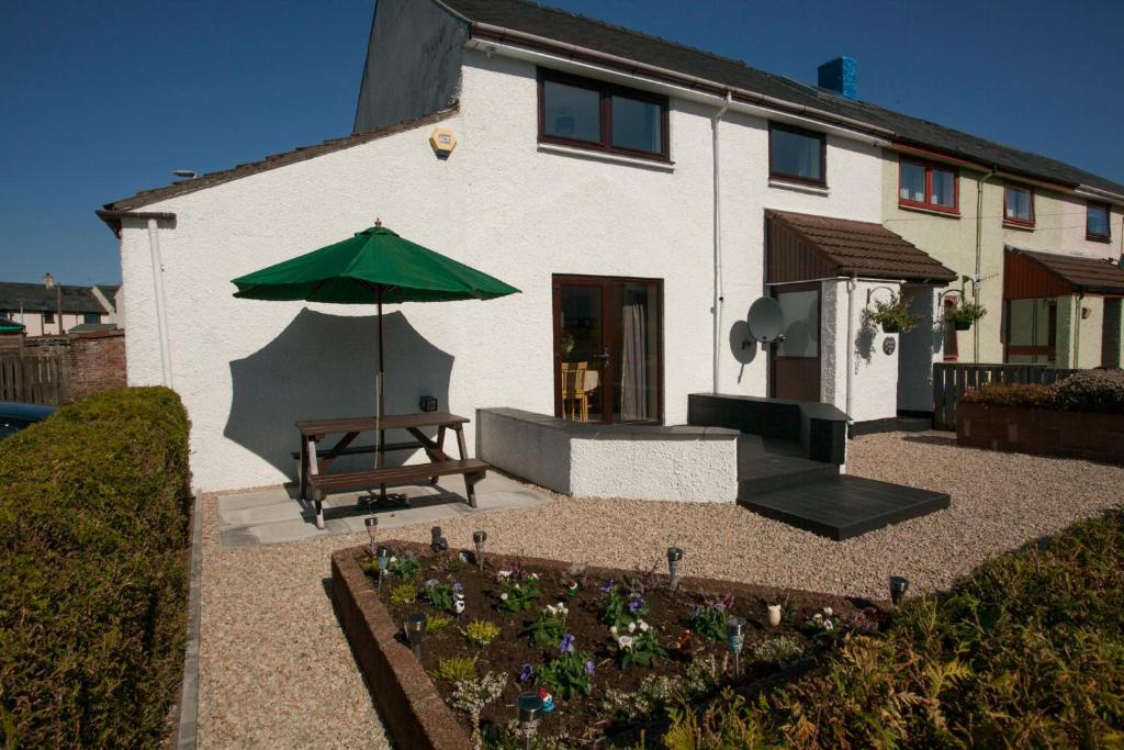 a patio with a table and an umbrella in front of a house at Fàilte Mhòr in Fort William