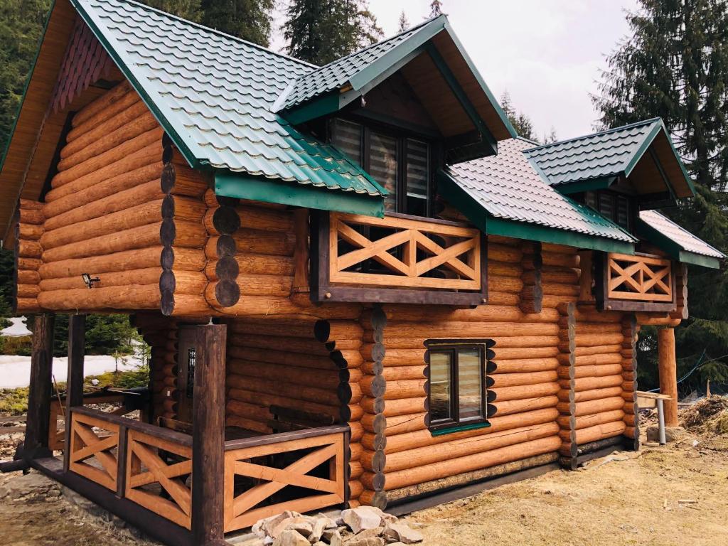 ein Blockhaus mit grünem Dach in der Unterkunft У ВІТИ котедж4 in Synewyrska Poljana