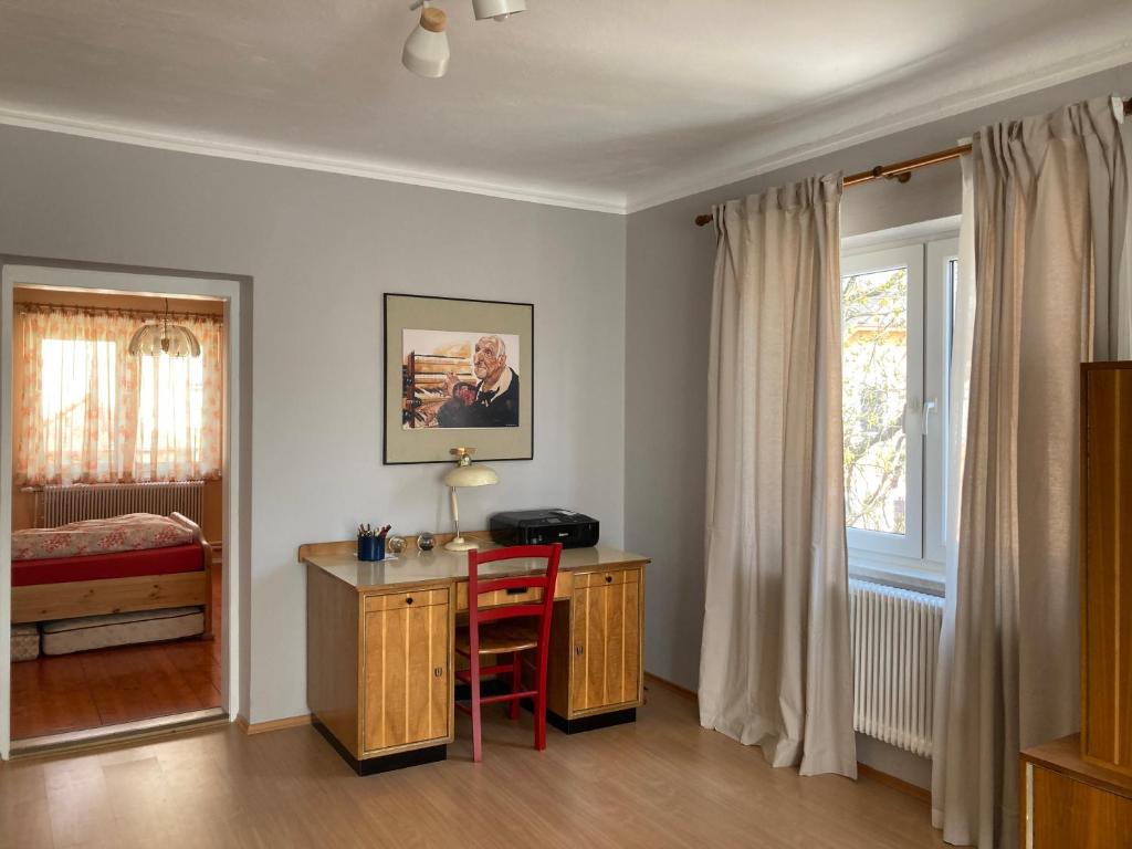 - une chambre avec un bureau, un lit et une chaise rouge dans l'établissement Baeckerei Mueller - große Unterkunft mit mid century Charme, zentral, sehr gut für Familien, privat, Stadt&Natur, Café im Haus, à Heidenreichstein