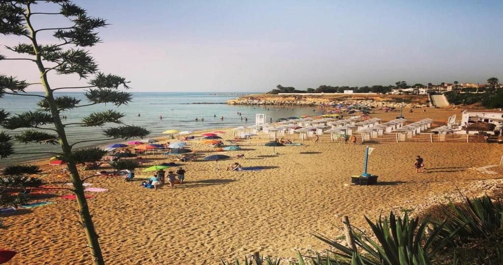 una playa con mucha gente, sombrillas y agua en B&B Costa Sicula, en Avola