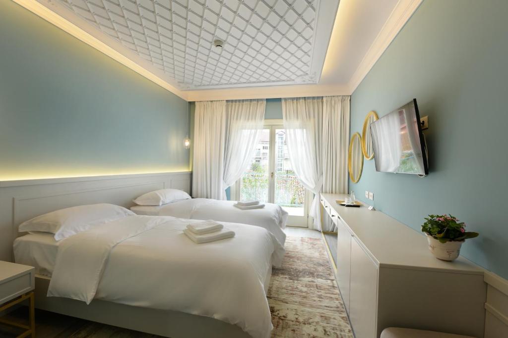 two beds in a hotel room with a window at Çoçja Boutique Hotel in Shkodër