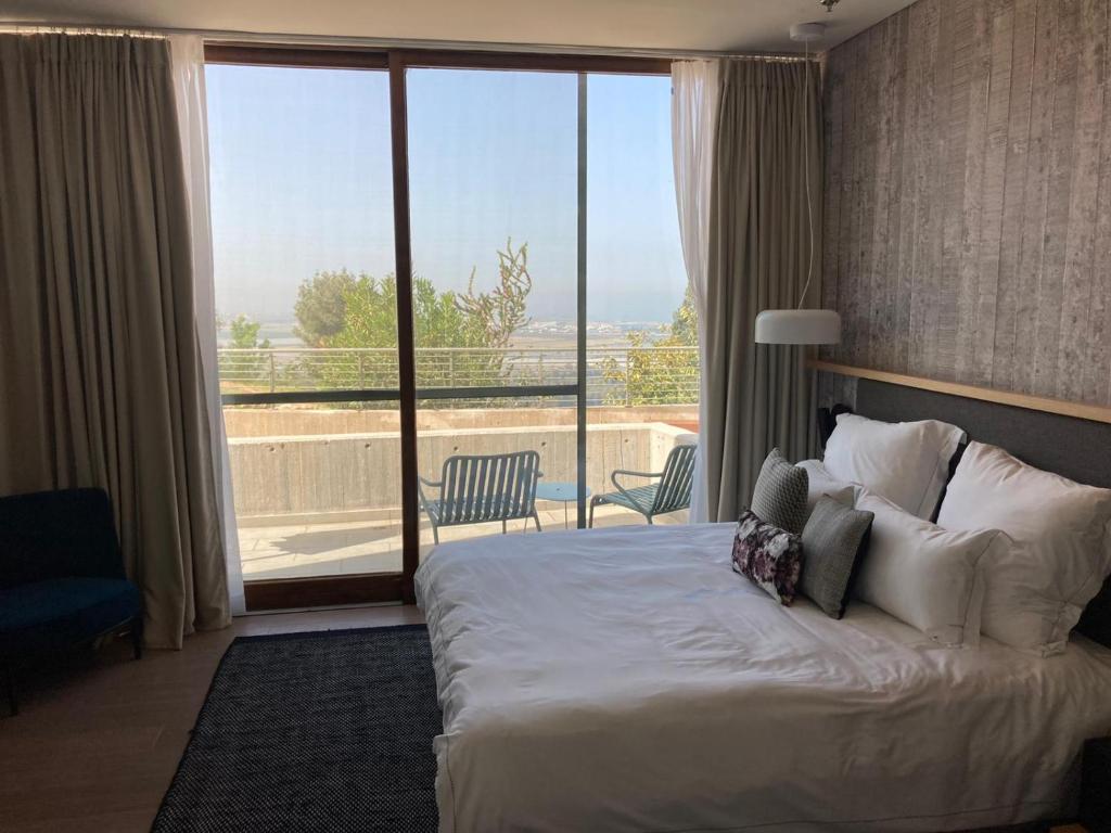a hotel room with a bed and a large window at Elma Hotel and Art Complex in Zikhron Ya'akov