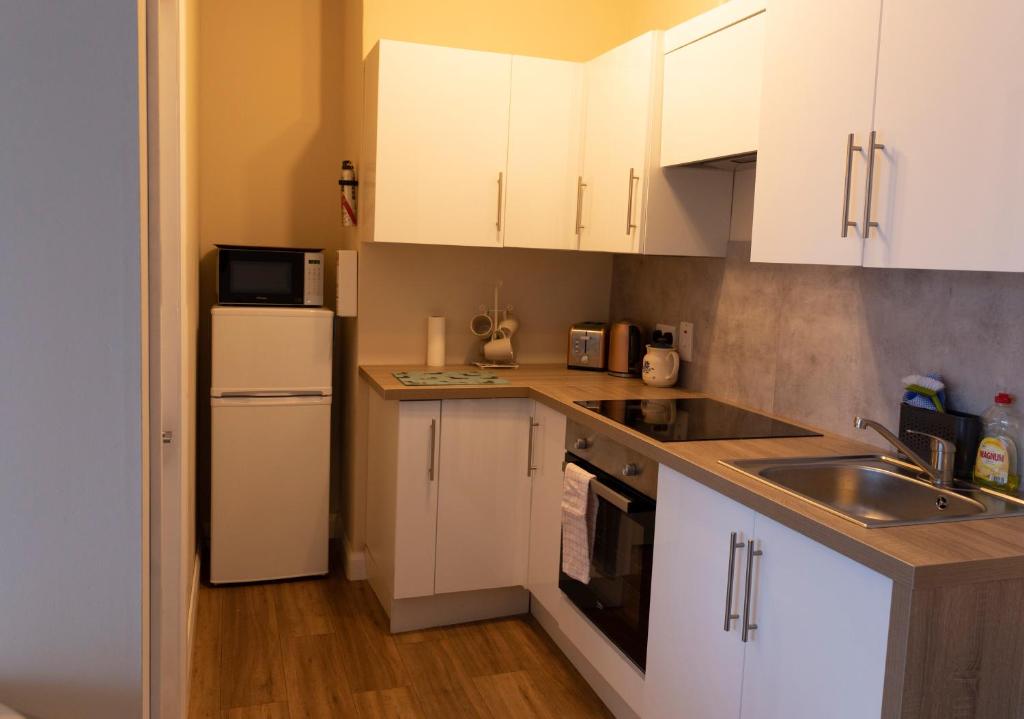 a kitchen with white cabinets and a sink and a refrigerator at Barrybeag 1 bedroom Apartments in Ballyvaughan