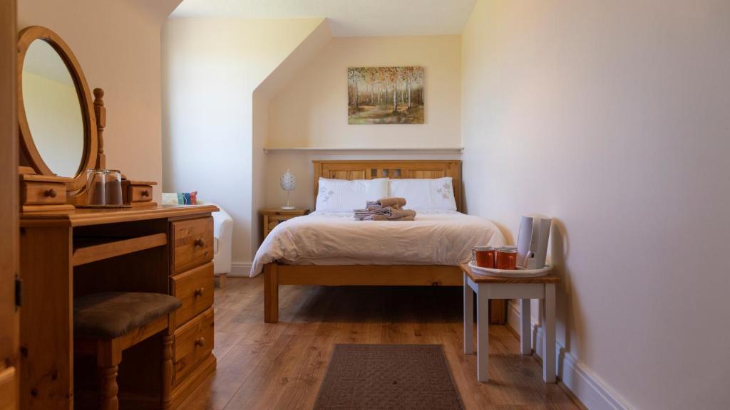 a bedroom with a bed and a dresser and a mirror at Barrymor Twin, Family and Double Room in Ballyvaughan