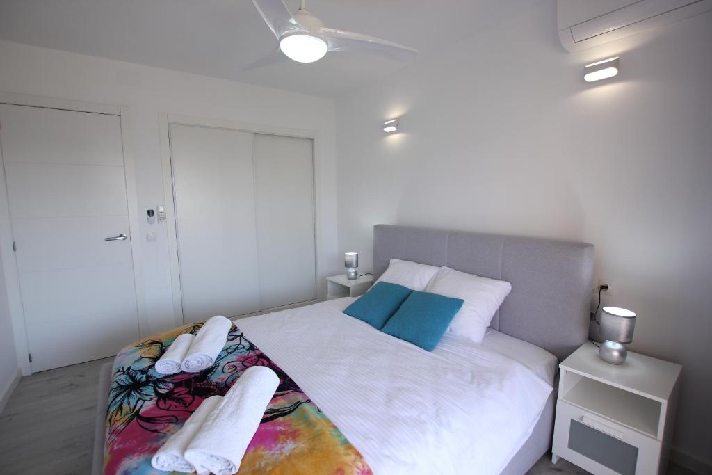 una camera da letto con un letto con lenzuola bianche e cuscini blu di La Playa Blanca7, El Palmeral, BEACH, SEA VIEW, POOL, WIFI a Torrevieja