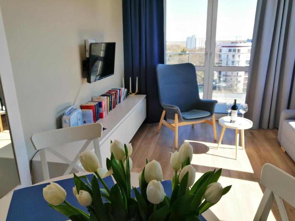 a living room with a blue chair and a table with flowers at Cicha Przystań Apartamenty Platany in Kołobrzeg