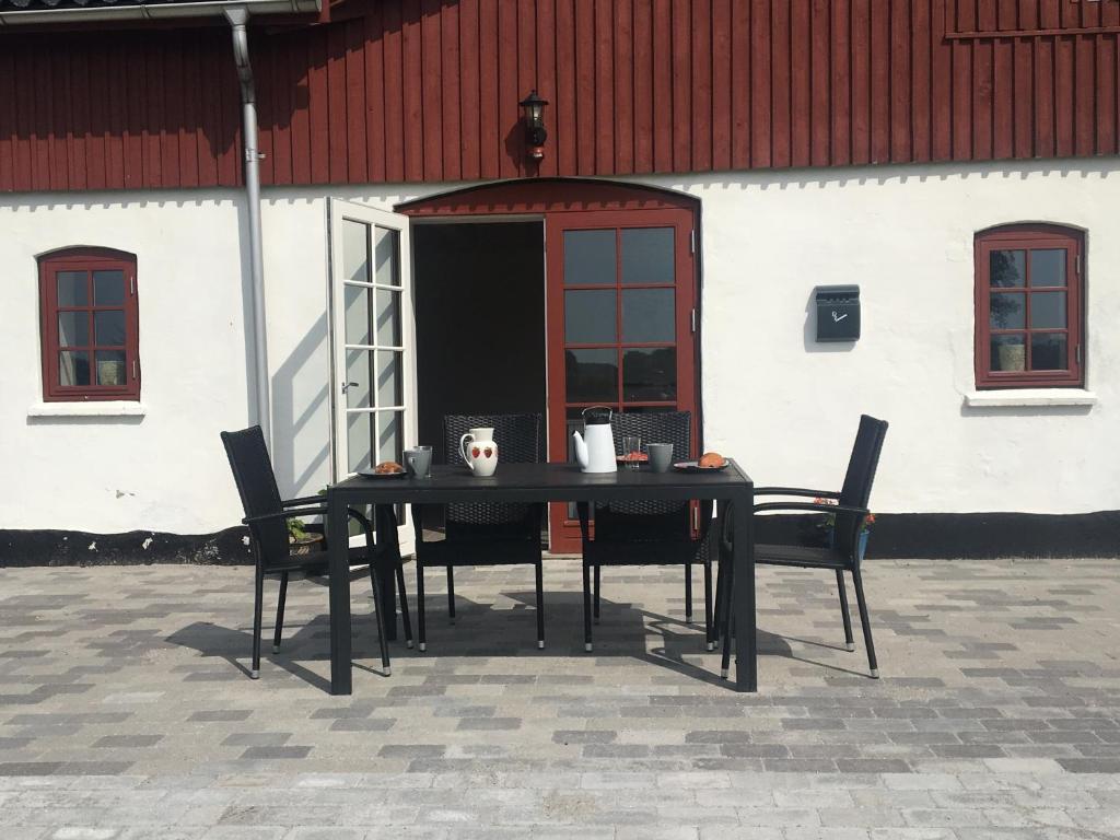 a black table and chairs in front of a building at Vita og Pouls Gård - Guesthouse in Viby