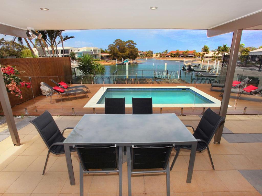 a table and chairs in front of a swimming pool at 4 bedroom home on canal in Mooloolaba