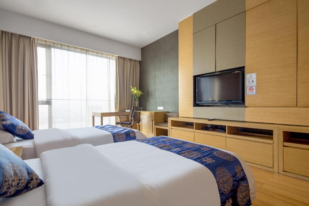 a hotel room with two beds and a flat screen tv at Si Lin Apartment in Guangzhou