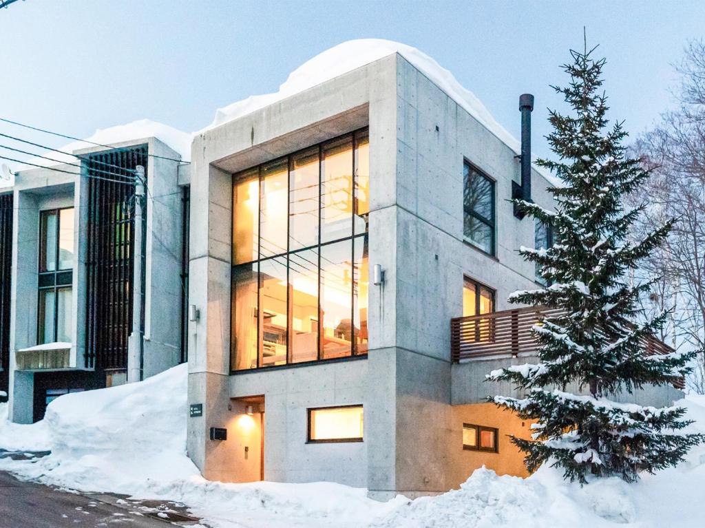 Una casa en la nieve con un árbol de Navidad en Kita Kitsune Chalet, en Kutchan