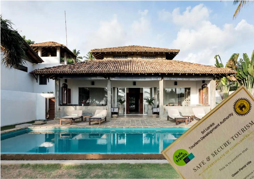 un cartel frente a una villa con piscina en Greenparrot-Villa, en Ambalangoda