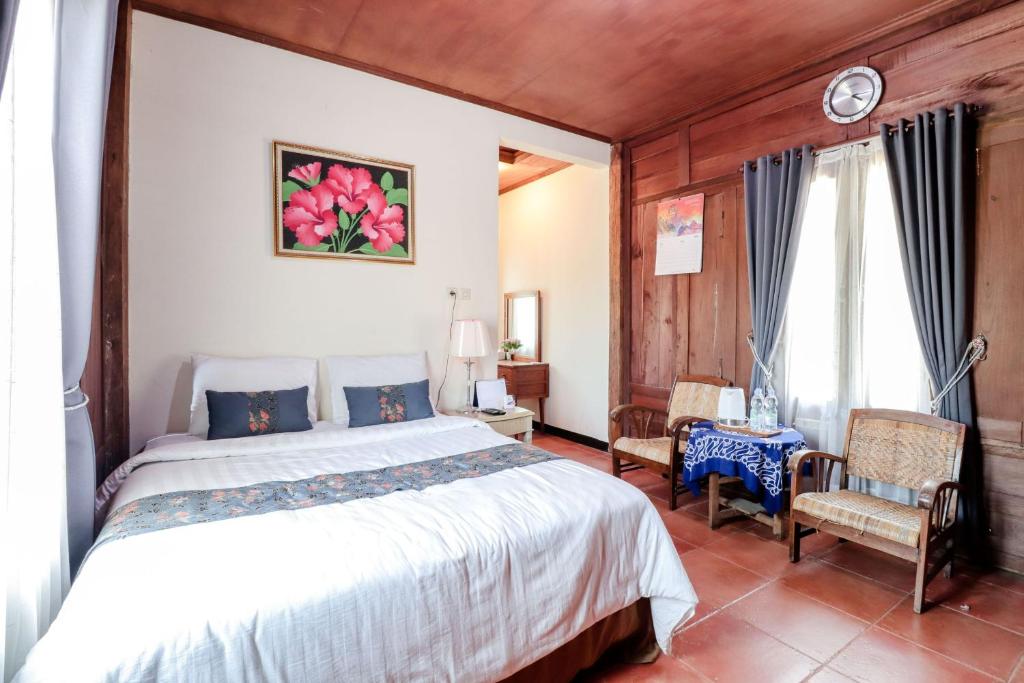 a bedroom with a large bed and two chairs at Balkondes Duta Menoreh in Magelang
