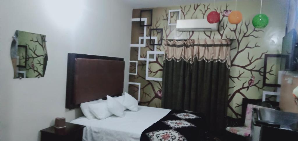 a bedroom with a bed and a wall with a curtain at Homewood Suite - Rooms & Appartments in Lahore