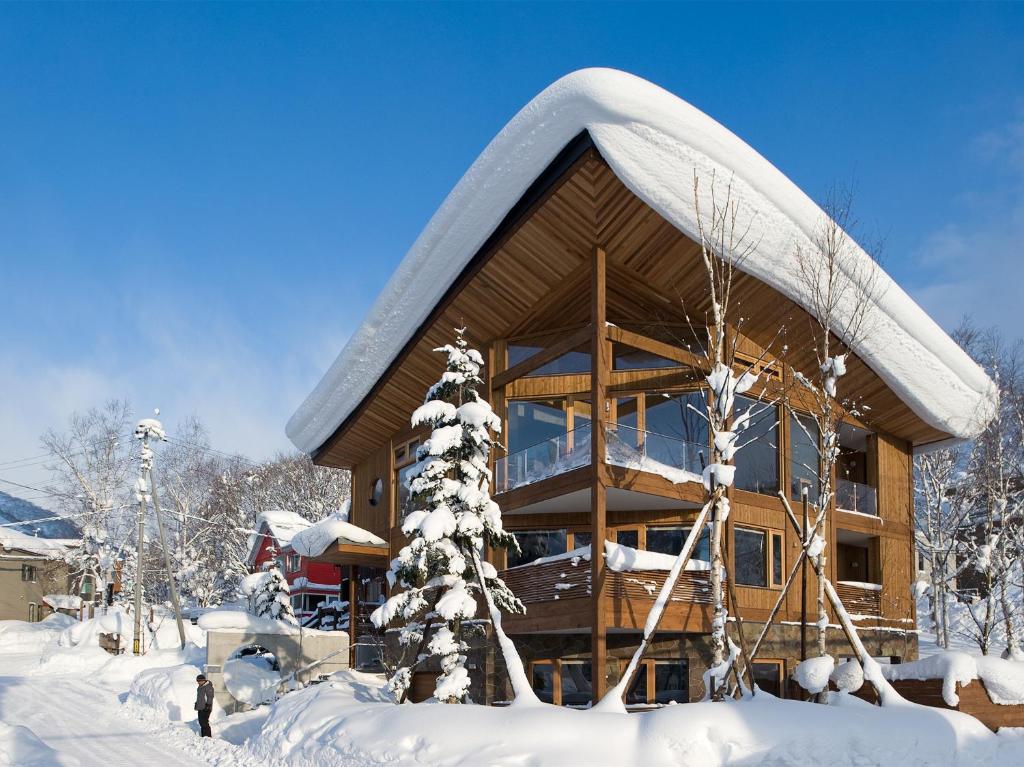 een blokhut in de sneeuw met sneeuw bedekte bomen bij Seshu Chalet in Niseko