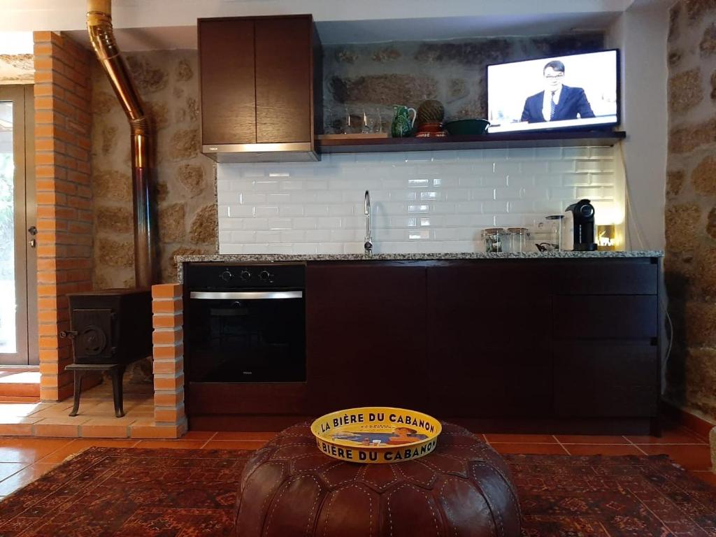 a kitchen with a stove and a tv on the wall at Anibals Boutique Lodging - Serra da Estrela in Gouveia