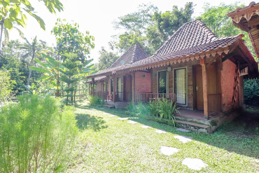 a small brick house with a garden in front of it at Balkondes Kenalan in Magelang