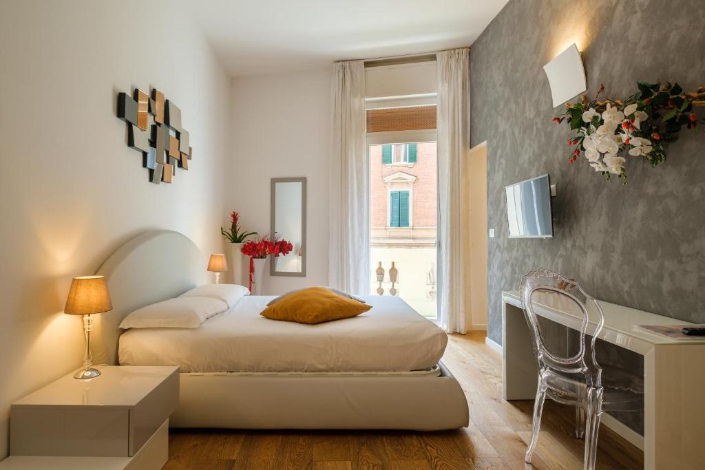 1 dormitorio con cama, escritorio y ventana en Tempobiancosuites, en Bolonia