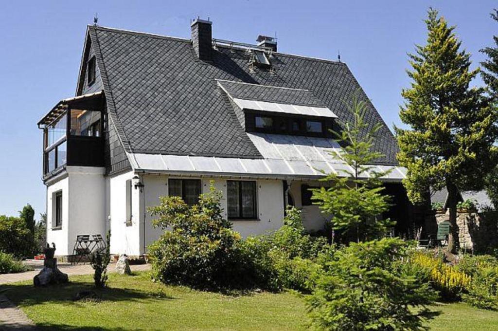 ein großes weißes Haus mit grauem Dach in der Unterkunft Ferienwohnung Haus Sonnenhügel in Kurort Altenberg