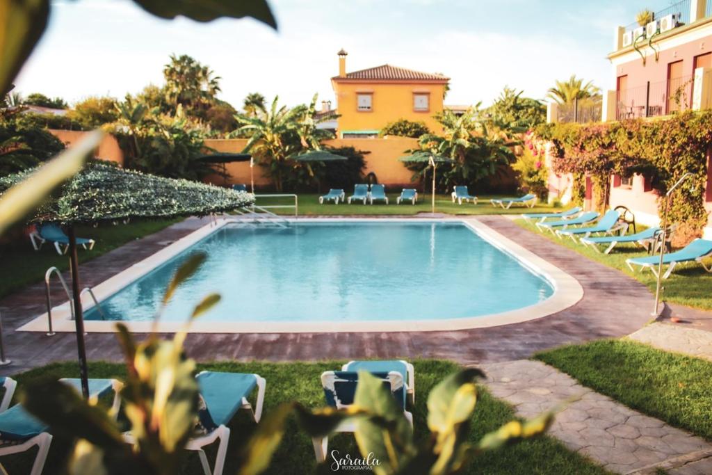 ein Swimmingpool in einem Garten mit Stühlen und einem Gebäude in der Unterkunft Hotel Pinomar in El Puerto de Santa María