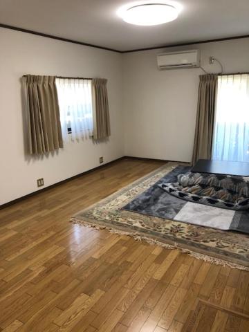 een lege woonkamer met een houten vloer en ramen bij 民泊ドリームルーカー in Haranomachi
