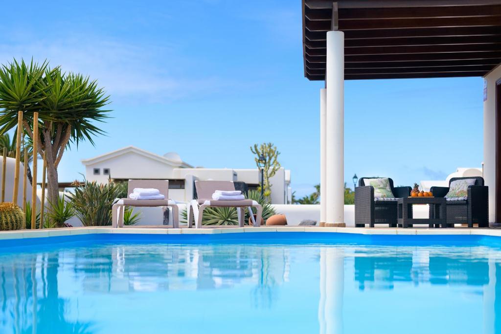 einen Pool mit Stühlen und ein Haus in der Unterkunft Casa La Goleta, Volcán y Mar in Playa Blanca