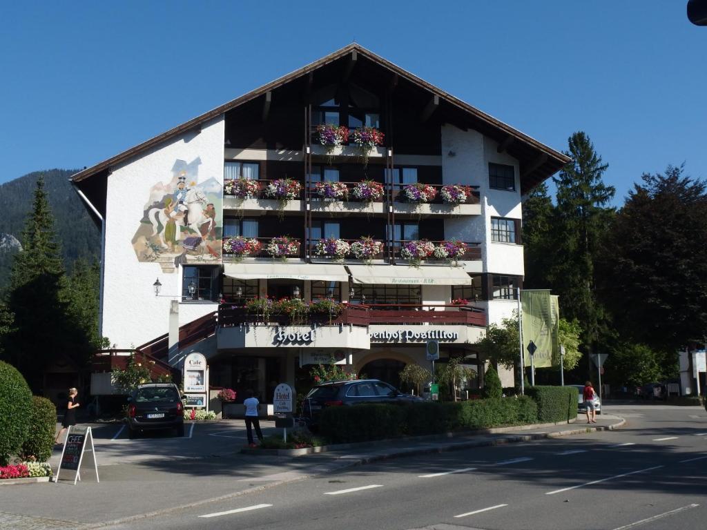 un bâtiment avec des fleurs sur ses balcons dans l'établissement Hotel Alpenhof Postillion, à Kochel am See
