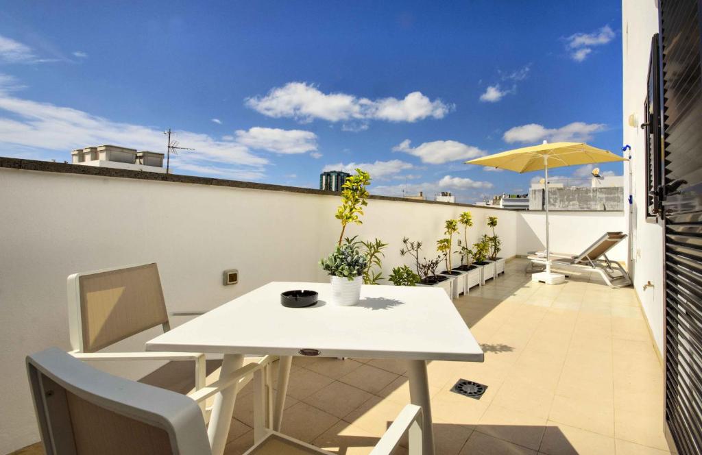 een witte tafel en stoelen op een balkon met een parasol bij La Casa de Lela in Arrecife