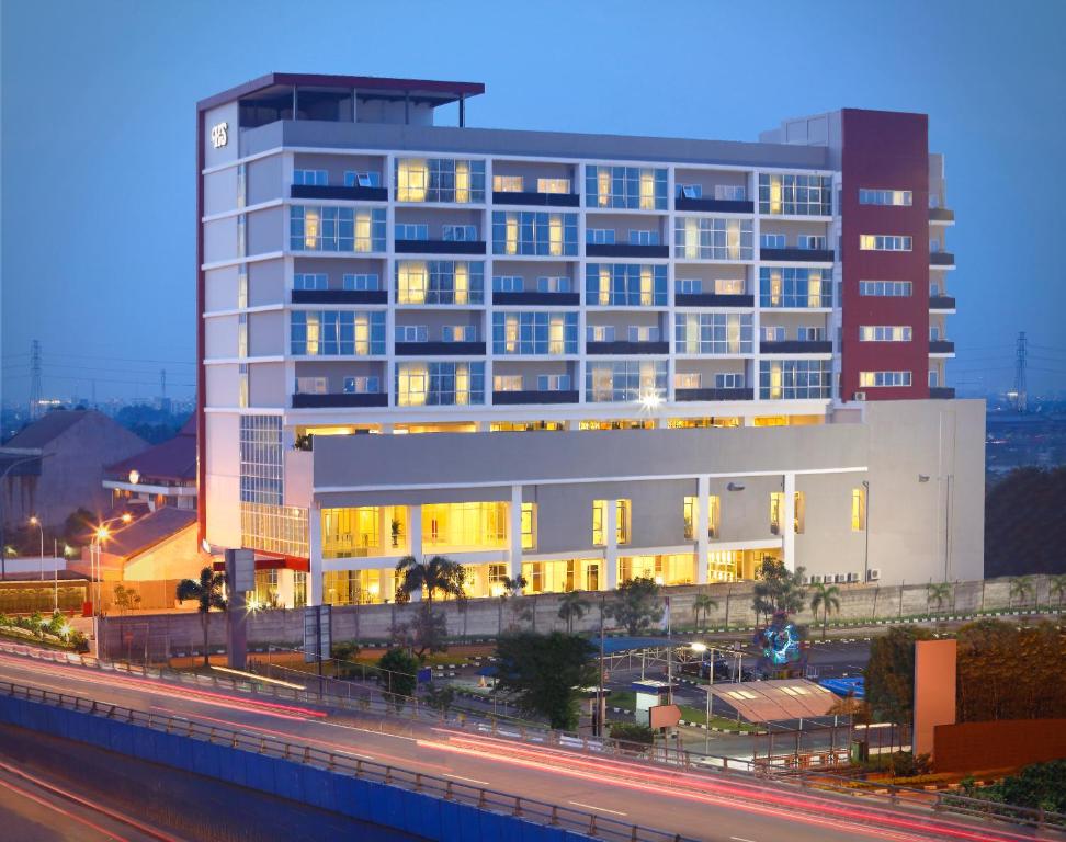 a large white building with lights on in a city at Hotel Santika Cikarang in Cikarang