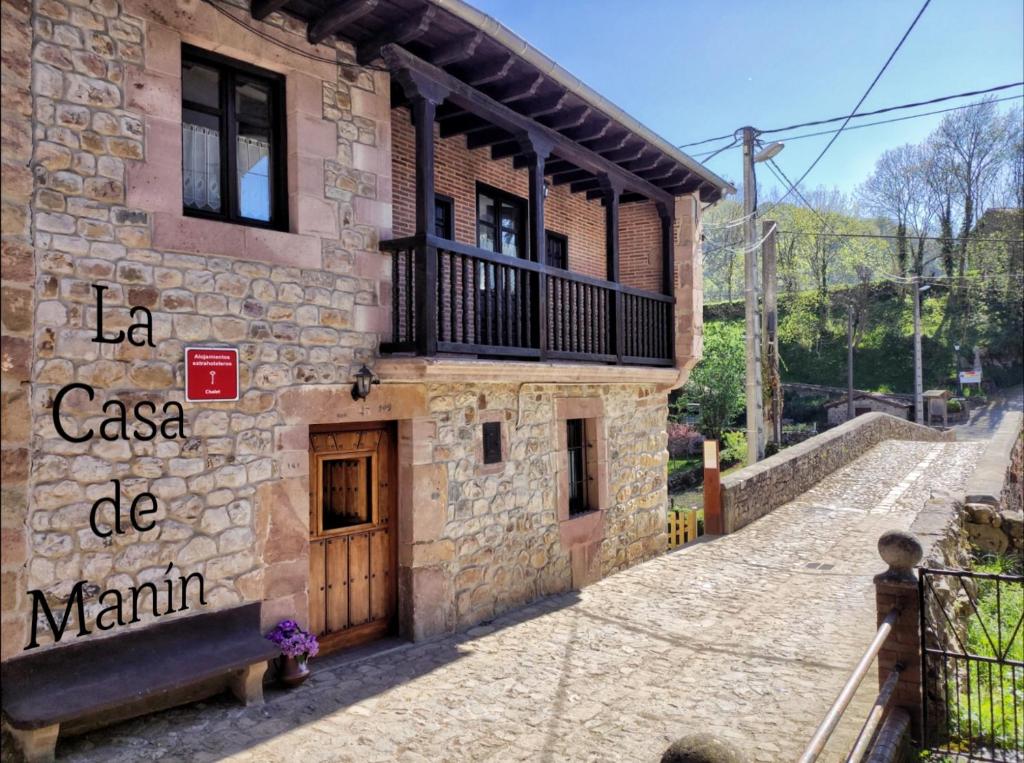 ein Steingebäude mit einer Holztür und einem Balkon in der Unterkunft La casa de Manín in San Sebastián de Garabandal
