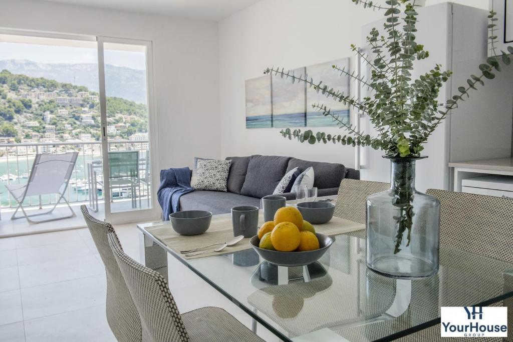 ein Wohnzimmer mit einem Glastisch mit einer Obstschale darauf in der Unterkunft YourHouse Es Niu, apartment in Puerto de Sóller in Sóller
