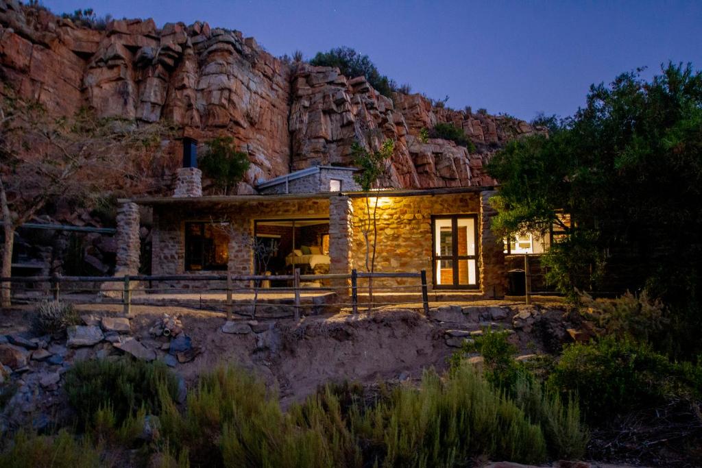 a stone house with a mountain in the background at Desert Wind Private Guest and Game Farm in Montagu