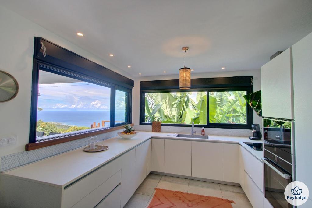 a kitchen with white cabinets and a large window at Villa Paloma 4 étoiles avec Piscine et Vue exceptionnelle sur l&#39;ocean à Saint-Leu in Saint-Leu